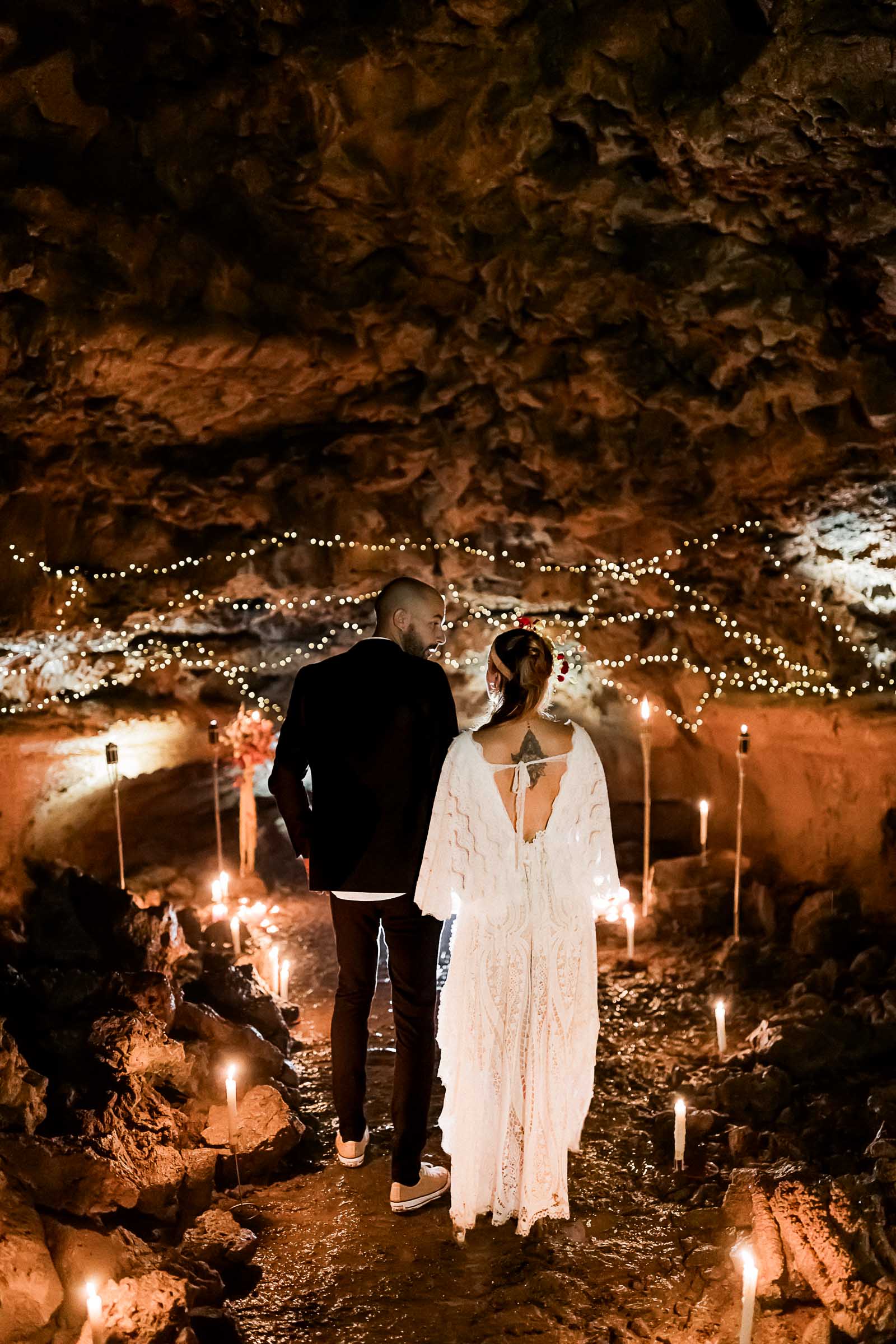 Photographie de Mathieu Dété, photographe de mariage sur l'île de la Réunion à Saint-Pierre, présentant un couple face à la décoration de leur cérémonie sous terre dans le tunnel de lave du Bassin Bleu de Saint-Gilles