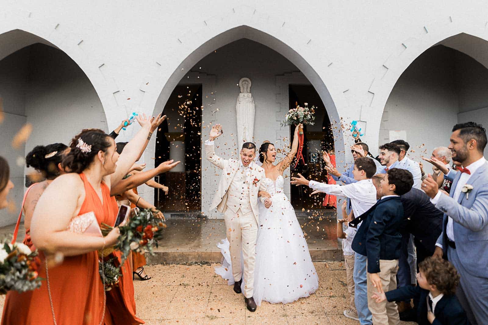 Photographie de Mathieu Dété, photographe de mariage et famille à Saint-Pierre sur l'île de la Réunion 974, présentant la sortie des mariés devant l'église de Saint-Gilles, devant leurs invités