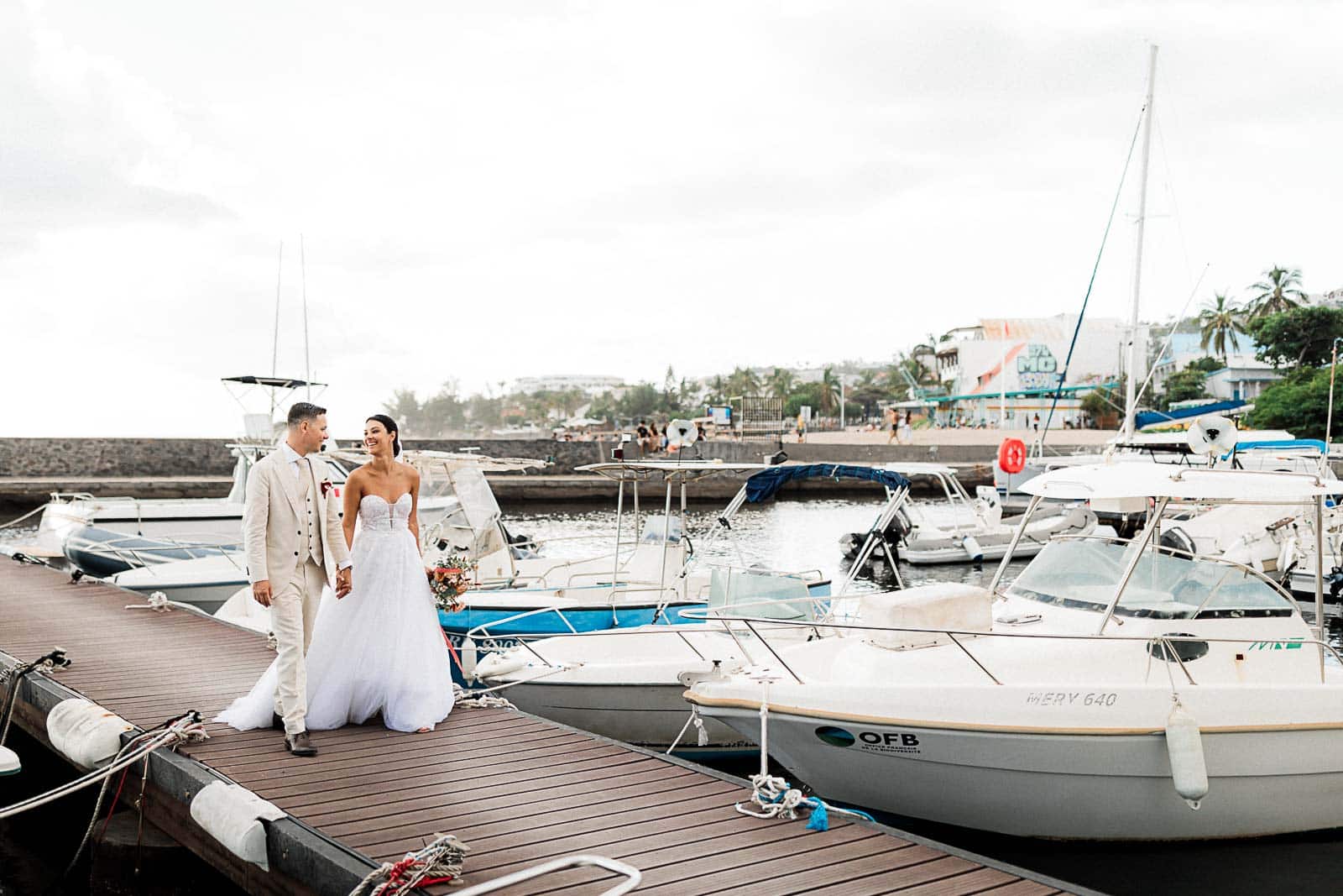 Photographie de Mathieu Dété, photographe de mariage et famille à Saint-Gilles sur l'île de la Réunion 974, présentant les mariés marchant côte à côte sur le port de Saint-Gilles-les-Bains