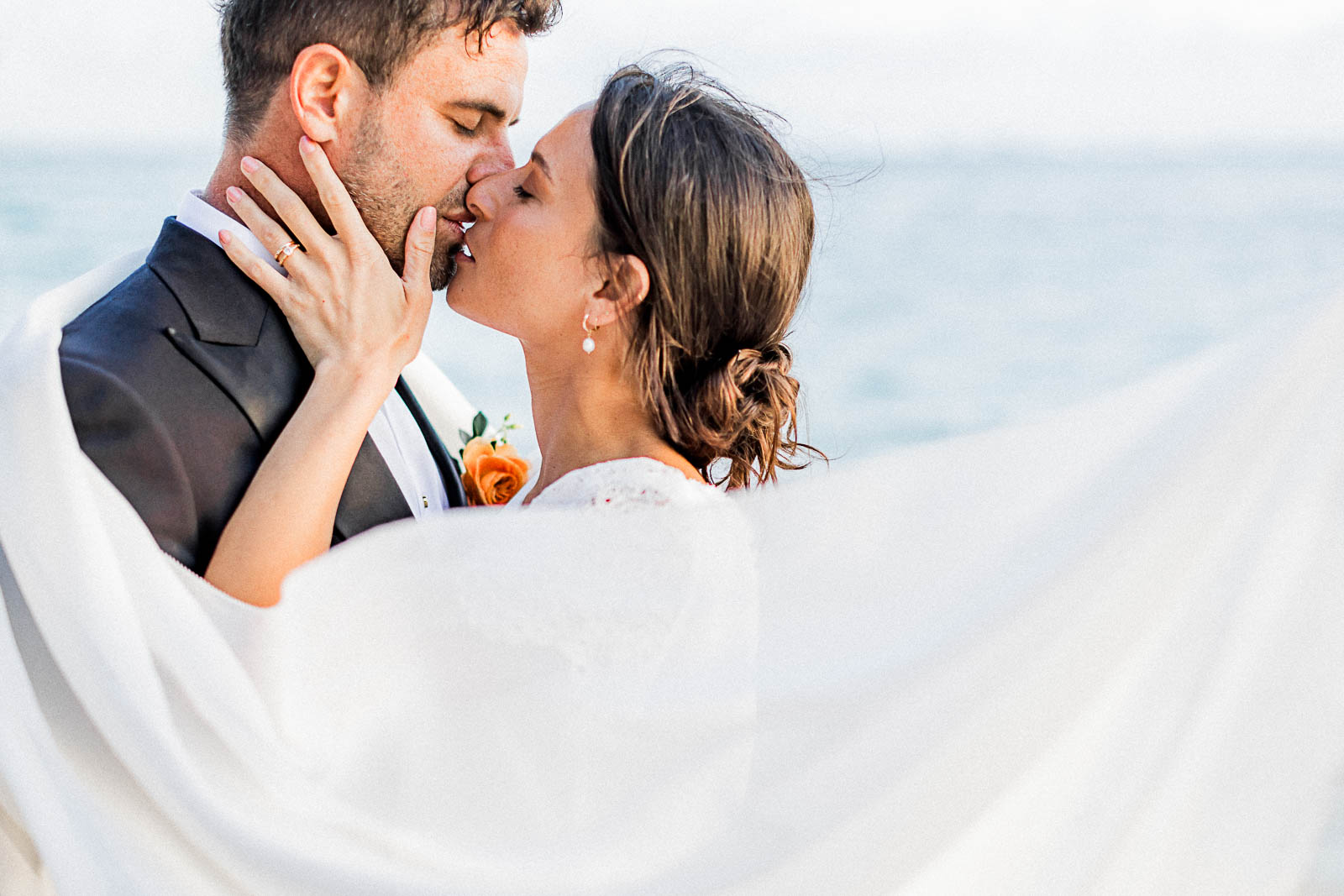 Photographie de Mathieu Dété, photographe de mariage sur l'île de la Réunion à la Saline-les-Bains, présentant un couple enlacé avec le voile de la mariée, en bord de mer