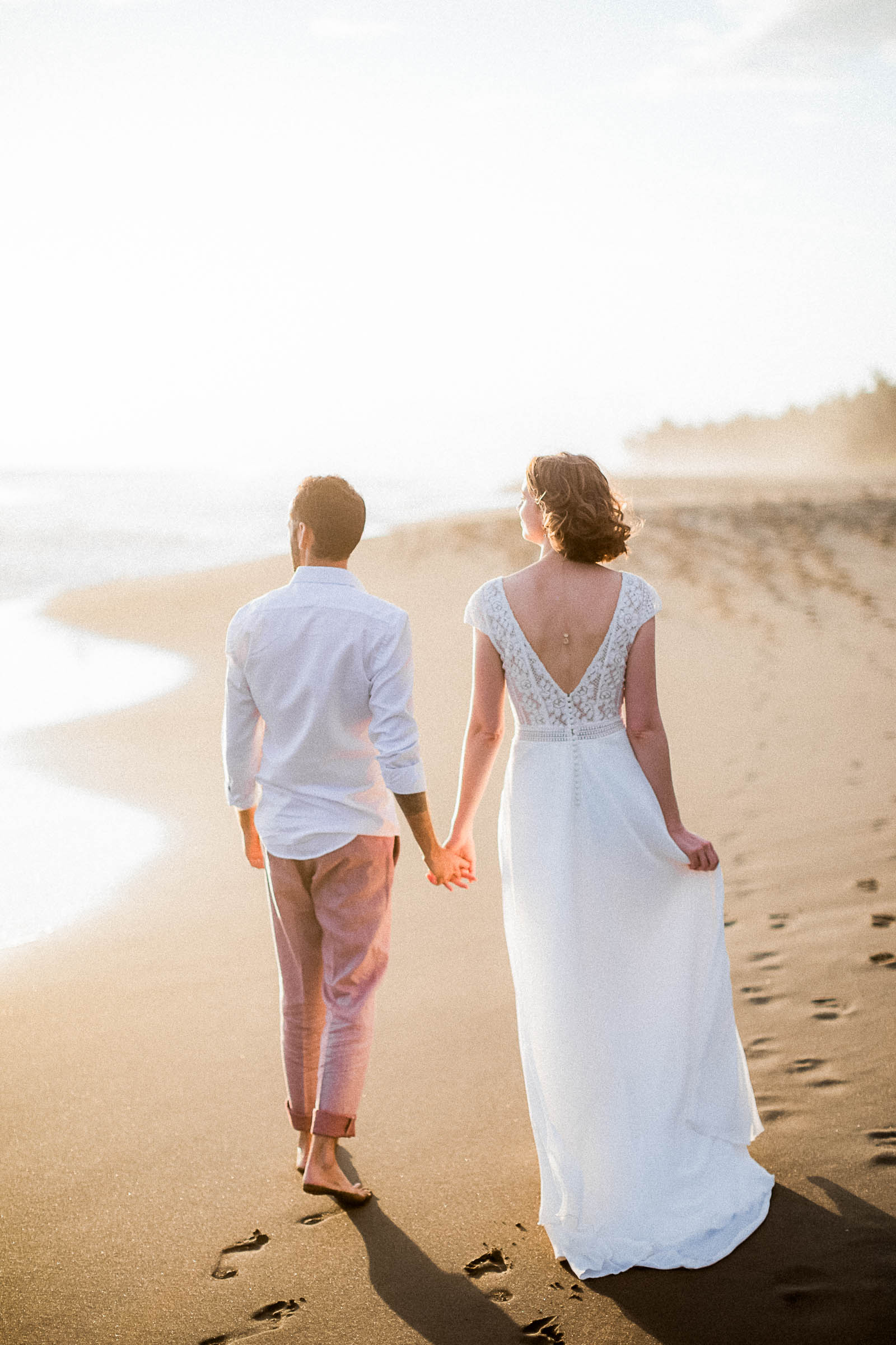 Photographie de Mathieu Dété, photographe de mariage sur l'île de la Réunion et dans l'Océan Indien, présentant un couple qui marche sur la plage à Etang-Salé-les-Bains, au coucher du soleil