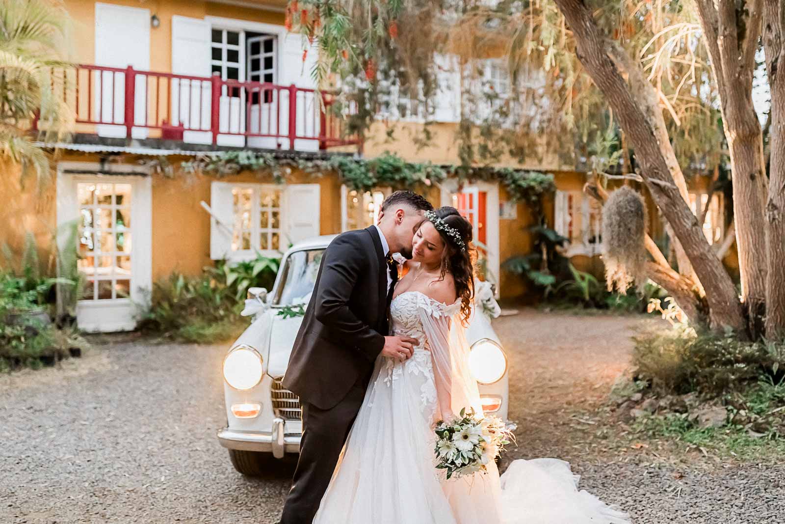 Photographie de Mathieu Dété, photographe de mariage sur l'île de la Réunion et en France, présentant un couple enlacé devant une vieille voiture, à la Villa Laurina de Saint-Paul