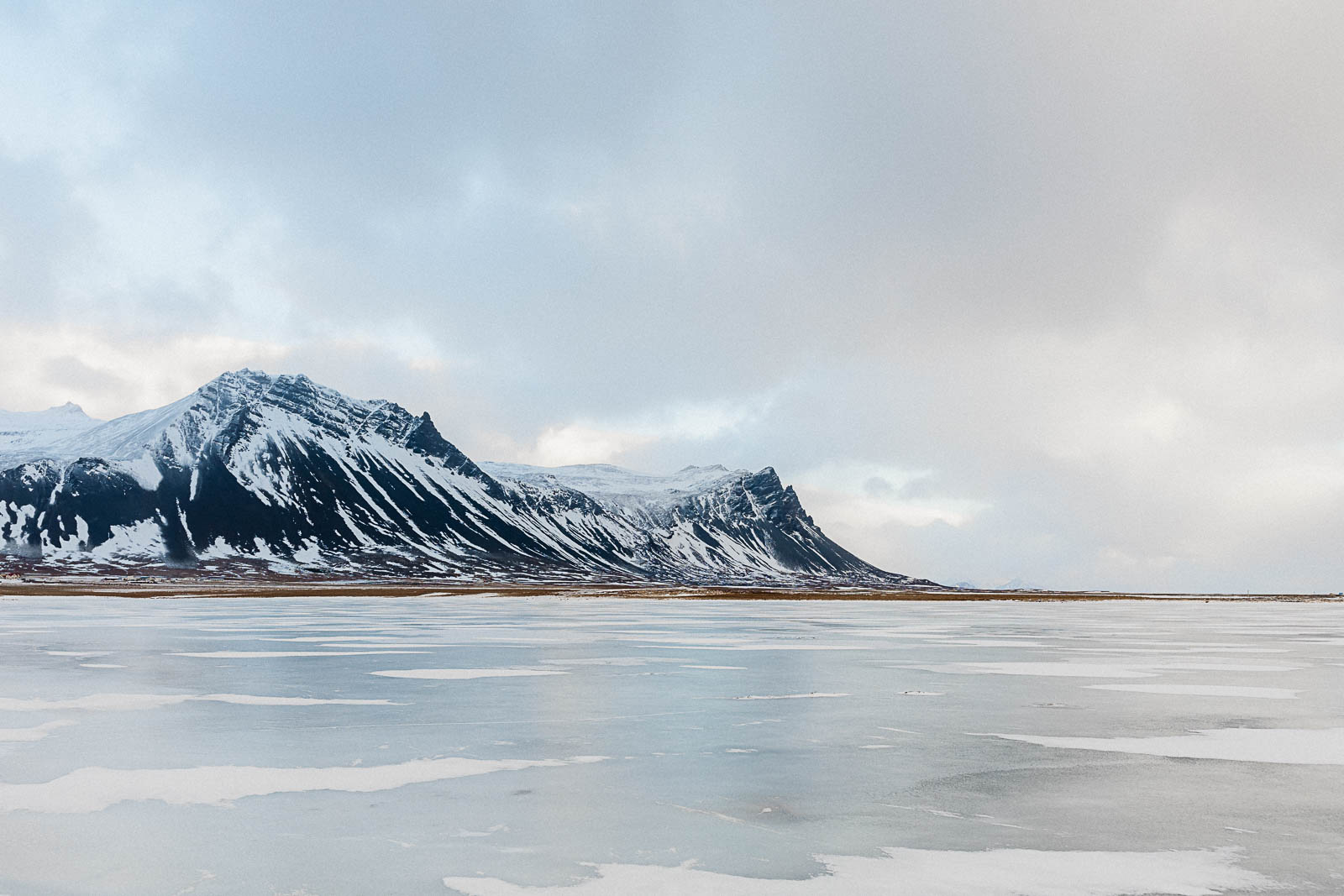 Photographie de Mathieu Dété, photographe de mariage et de voyage à la Réunion, présentant une photo de montagnes enneigées devant un lac de glace, lors d'un voyage en Islande