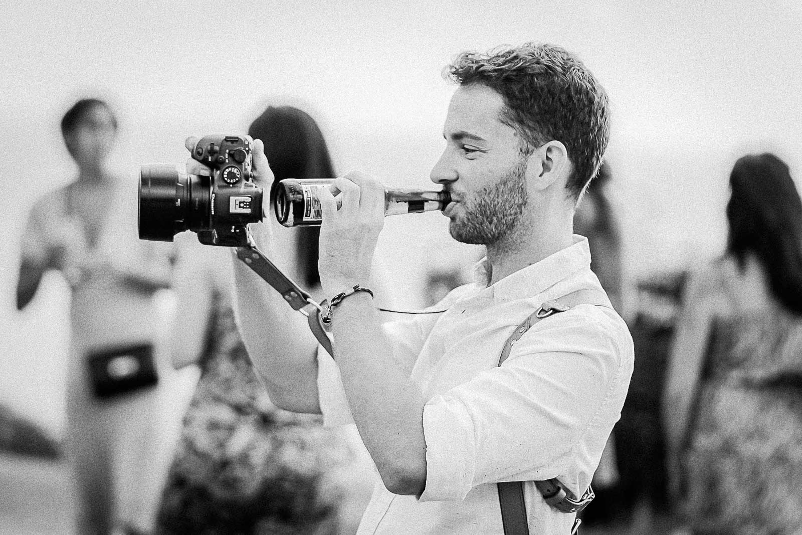 Photographie de Mathieu Dété, photographe de mariage à la Réunion, me présentant lors d'un mariage avec une bière et un appareil photo à la main